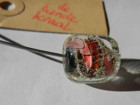 een handgemaakte glaskraal van De Tiende Kraal met kleuren als vuur